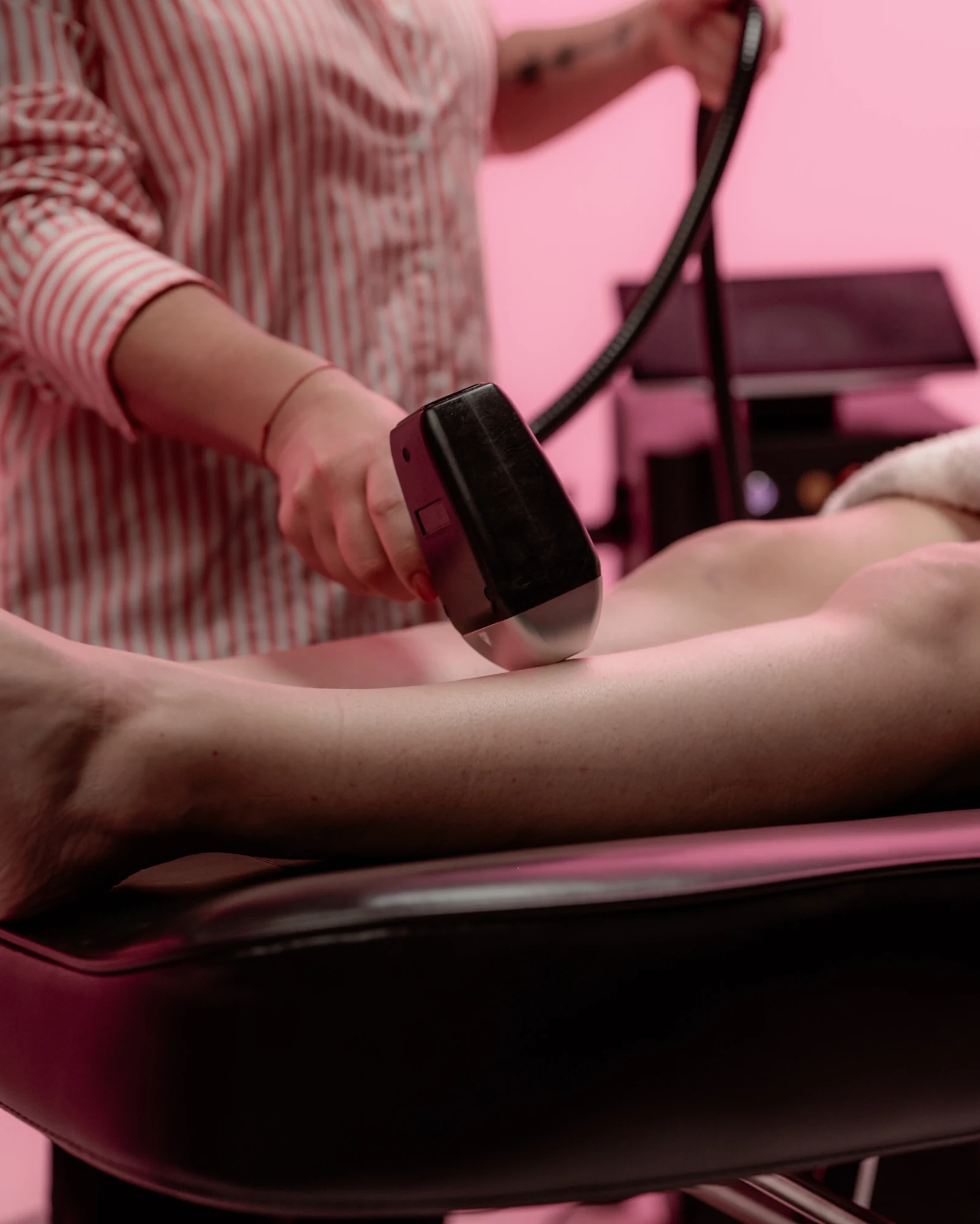 Séance d'épilation laser chez AlyCare : la praticienne applique la pièce à main du laser sur l'avant-bras d'une cliente allongée.